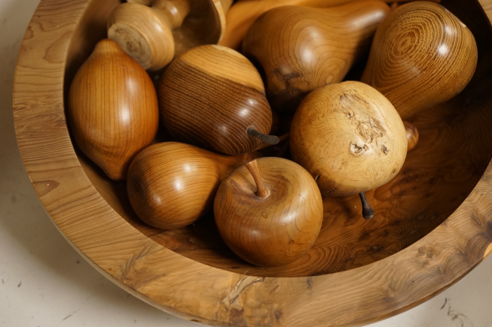 A modern treen yew bowl, a burr wood bowl and various fruit